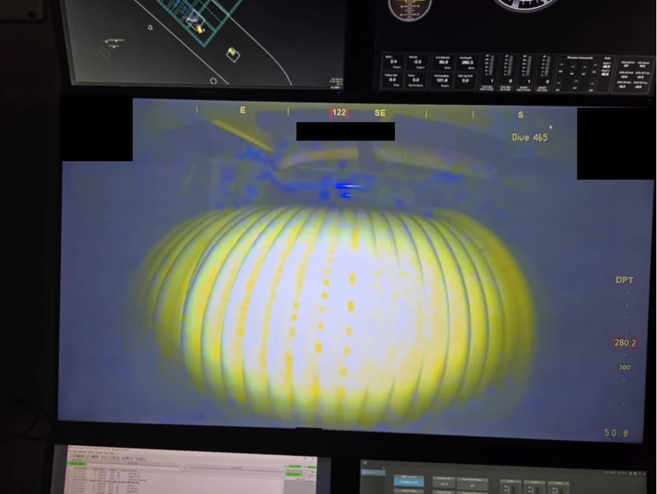 Kontrollromsskjerm med ROV-kamerabilde av en gul kabeltrommel: sterkt, overeksponert lys i midten og mørkere, blåtonede partier rundt